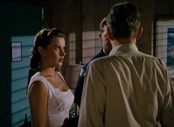 Movie still from “Niagara” (1953), directed by Henry Hathaway – A man and a woman standing next to each other in front of another man; Medium shot, Over the shoulder angle