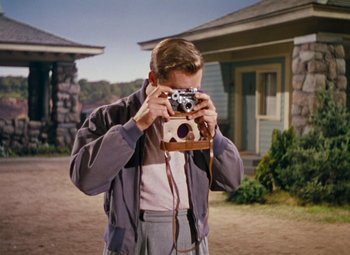 Movie still from “Niagara” (1953), directed by Henry Hathaway – A man holding a camera in front of his face; Medium shot, Over the shoulder angle