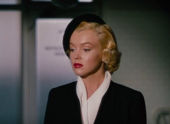 Movie still from “Niagara” (1953), directed by Henry Hathaway – A woman with blonde hair wearing a black suit and a hat; Close Up shot, Over the shoulder angle