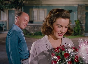 Movie still from “Niagara” (1953), directed by Henry Hathaway – A man and a woman standing next to each other holding flowers; Medium shot, Over the shoulder angle