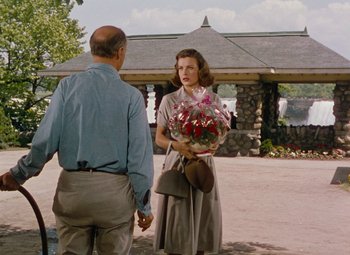 Movie still from “Niagara” (1953), directed by Henry Hathaway – An older man and a woman holding hands and talking; Medium shot, Over the shoulder angle