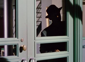 Movie still from “Niagara” (1953), directed by Henry Hathaway – A man wearing a hat looking out of a door; Medium shot, Low angle