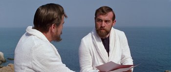 Movie still from “Nicholas and Alexandra” (1971), directed by Franklin J. Schaffner – A man in a white bathrobe is talking to another man in a white robe; Medium shot, Over the shoulder angle