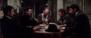 Movie still from “Nicholas and Alexandra” (1971), directed by Franklin J. Schaffner – A group of men sitting around a table with a lit candle; Medium shot, High angle