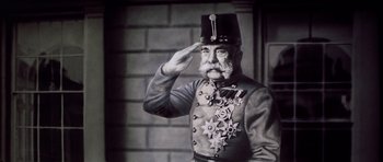 Movie still from “Nicholas and Alexandra” (1971), directed by Franklin J. Schaffner – An older man in a uniform saluting with a hat on his head; Close Up shot, Low angle