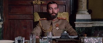 Movie still from “Nicholas and Alexandra” (1971), directed by Franklin J. Schaffner – A man sitting at a table wearing a military uniform; Medium shot, Low angle
