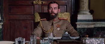 Movie still from “Nicholas and Alexandra” (1971), directed by Franklin J. Schaffner – A man sitting at a table wearing a military uniform; Medium shot, Low angle