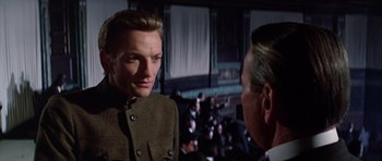 A man in a military uniform talking to another man in a suit