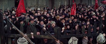 Movie still from “Nicholas and Alexandra” (1971), directed by Franklin J. Schaffner – A group of people standing next to each other in front of a wooden fence; Wide shot, High angle