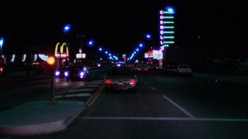 Movie still from “Night Moves” (1975), directed by Arthur Penn – Cars driving down a street at night with lights on; Extreme Wide shot, Low angle