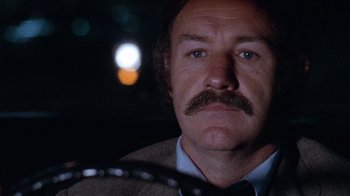 Movie still from “Night Moves” (1975), directed by Arthur Penn – A person with a mustache in a car; Close Up shot, Low angle