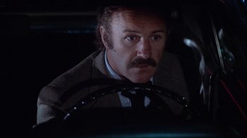 Movie still from “Night Moves” (1975), directed by Arthur Penn – A man with a mustache sitting in the drivers seat of a car; Close Up shot, Low angle