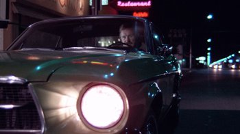 Movie still from “Night Moves” (1975), directed by Arthur Penn – A man sitting in the driver's seat of an old car; Medium shot, Low angle