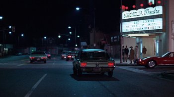 Movie still from “Night Moves” (1975), directed by Arthur Penn – Cars driving down a street at night in the dark; Wide shot, Low angle