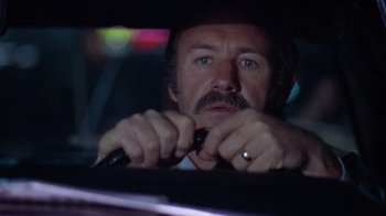 Movie still from “Night Moves” (1975), directed by Arthur Penn – A person in a car holding a steering wheel; Close Up shot, Low angle