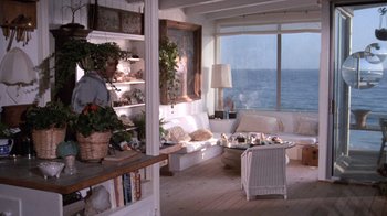 Movie still from “Night Moves” (1975), directed by Arthur Penn – A living room filled with lots of furniture and potted plants; Wide shot, High angle