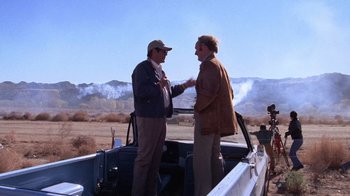 Movie still from “Night Moves” (1975), directed by Arthur Penn – Two men standing on a boat in the middle of a field; Wide shot, Over the shoulder angle