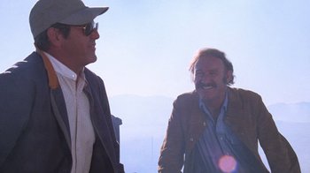 Movie still from “Night Moves” (1975), directed by Arthur Penn – Two men are talking to each other on a hill; Medium shot, Low angle