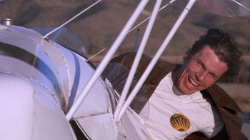 Movie still from “Night Moves” (1975), directed by Arthur Penn – A man smiling while sitting in a biplane; Close Up shot, Low angle