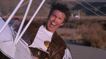 Movie still from “Night Moves” (1975), directed by Arthur Penn – A man in a leather jacket holding an umbrella; Close Up shot, Low angle