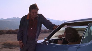 Movie still from “Night Moves” (1975), directed by Arthur Penn – A man standing next to a woman in a blue car; Medium shot, Over the shoulder angle