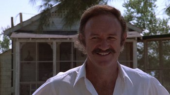 Movie still from “Night Moves” (1975), directed by Arthur Penn – A man in a white shirt smiling for the camera; Close Up shot, Low angle