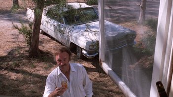 Movie still from “Night Moves” (1975), directed by Arthur Penn – A man standing next to an old white car; Wide shot, Low angle