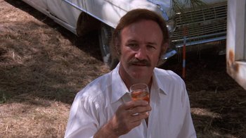 Movie still from “Night Moves” (1975), directed by Arthur Penn – A man holding a glass in his right hand; Close Up shot, Low angle