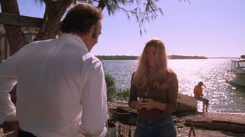 Movie still from “Night Moves” (1975), directed by Arthur Penn – A man and a woman standing next to a body of water; Medium shot, Over the shoulder angle
