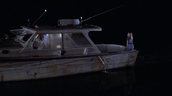 Movie still from “Night Moves” (1975), directed by Arthur Penn – A woman sitting on the back end of a boat at night; Wide shot, High angle