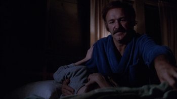 Movie still from “Night Moves” (1975), directed by Arthur Penn – A man sitting on a bed holding a baby; Close Up shot, Over the shoulder angle