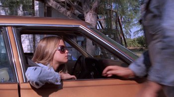 Movie still from “Night Moves” (1975), directed by Arthur Penn – A woman sitting in the driver's seat of an orange car; Medium shot, Low angle