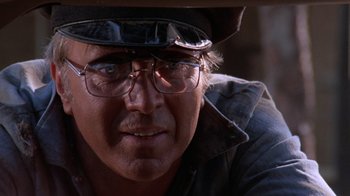 Movie still from “Night Moves” (1975), directed by Arthur Penn – An older man wearing glasses and a hat; Close Up shot, Low angle