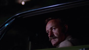 Movie still from “Night Moves” (1975), directed by Arthur Penn – A man with a mustache sitting in the back of a car; Close Up shot, Low angle