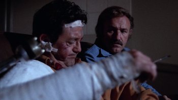 Movie still from “Night Moves” (1975), directed by Arthur Penn – Two men are in a room and one of them has a bandage on his head; Close Up shot, Over the shoulder angle