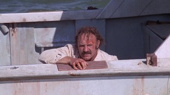 Movie still from “Night Moves” (1975), directed by Arthur Penn – A man leaning on a railing on a boat in the water; Medium shot, Low angle