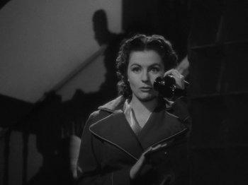 Movie still from “Night Train to Munich” (1940), directed by Carol Reed – A black - and - white photo of a woman holding a camera; Close Up shot, Low angle