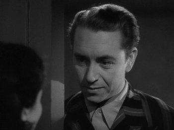 Movie still from “Night Train to Munich” (1940), directed by Carol Reed – An old photo of a man looking at the camera; Close Up shot, Over the shoulder angle