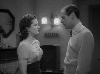 Movie still from “Night Train to Munich” (1940), directed by Carol Reed – A man and a woman standing next to each other in a room; Medium shot, High angle