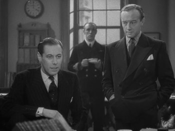 Movie still from “Night Train to Munich” (1940), directed by Carol Reed – A group of men standing next to each other in front of a window; Medium shot, Low angle