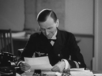 Movie still from “Night Train to Munich” (1940), directed by Carol Reed – A man sitting at a table reading a piece of paper; Close Up shot, Low angle