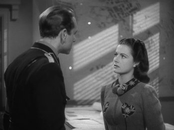 Movie still from “Night Train to Munich” (1940), directed by Carol Reed – A man and a woman are standing next to each other; Medium shot, Over the shoulder angle