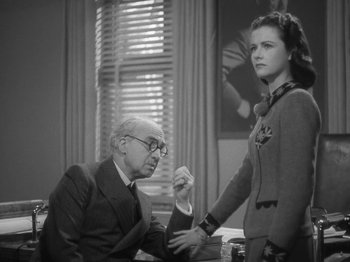 Movie still from “Night Train to Munich” (1940), directed by Carol Reed – An older man sitting next to a young woman in front of a window; Medium shot, Low angle