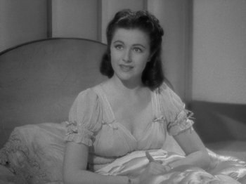 Movie still from “Night Train to Munich” (1940), directed by Carol Reed – An old black and white photo of a woman sitting on a couch; Close Up shot, High angle