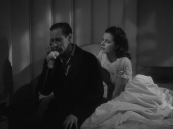 Movie still from “Night Train to Munich” (1940), directed by Carol Reed – A man and a woman sitting on a bed; Medium shot, High angle