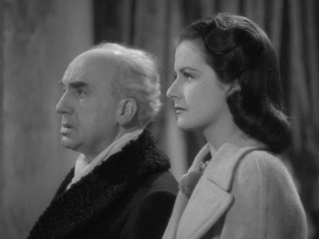Movie still from “Night Train to Munich” (1940), directed by Carol Reed – An older man and a younger woman standing next to each other; Close Up shot, Low angle