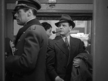 Movie still from “Night Train to Munich” (1940), directed by Carol Reed – A black and white photo of a man smoking a pipe; Medium shot, Low angle