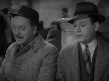 Movie still from “Night Train to Munich” (1940), directed by Carol Reed – A couple of men wearing hats and suits; Close Up shot, High angle