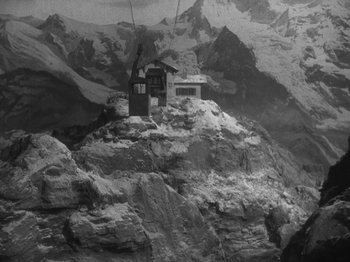 Movie still from “Night Train to Munich” (1940), directed by Carol Reed – A black and white photo of a cable car going up a mountain; Extreme Wide shot, High angle