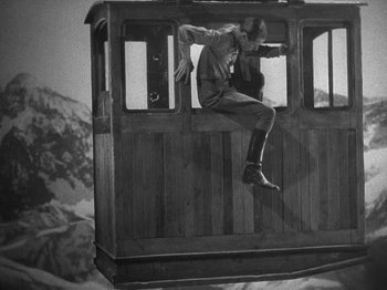 Movie still from “Night Train to Munich” (1940), directed by Carol Reed – A man jumping off of a train in the air; Wide shot, Low angle